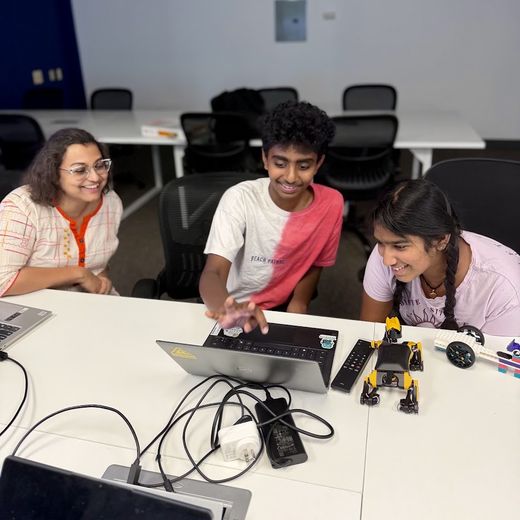 Instructor and two students testing robots at a laptop