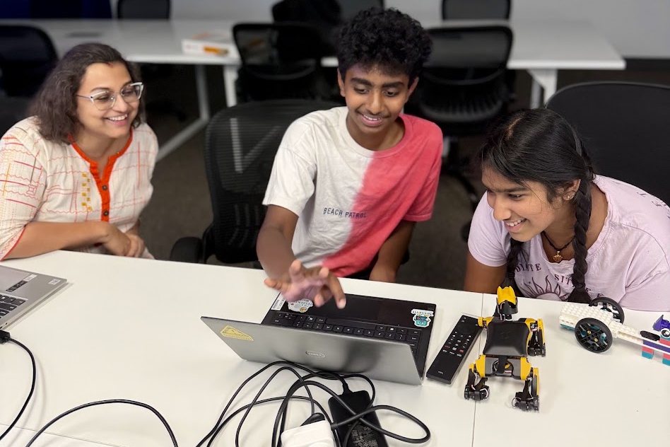 Two students and an instructor programming robots together