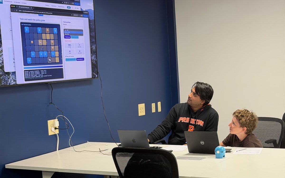 An instructor and student watching an AI model learn a task on screen